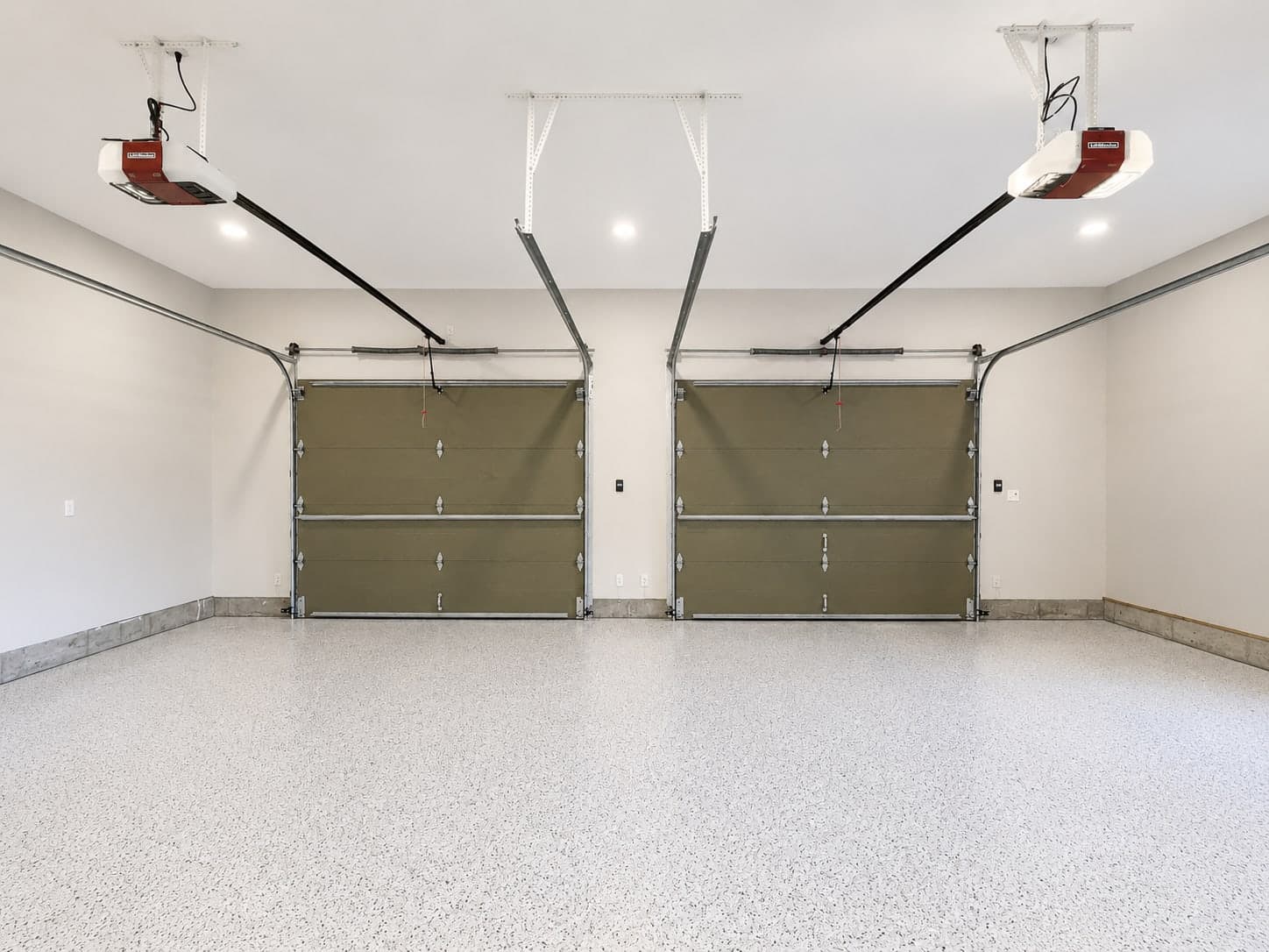 Two-car garage with a freshly installed flake epoxy floor, doors and walls finished in white