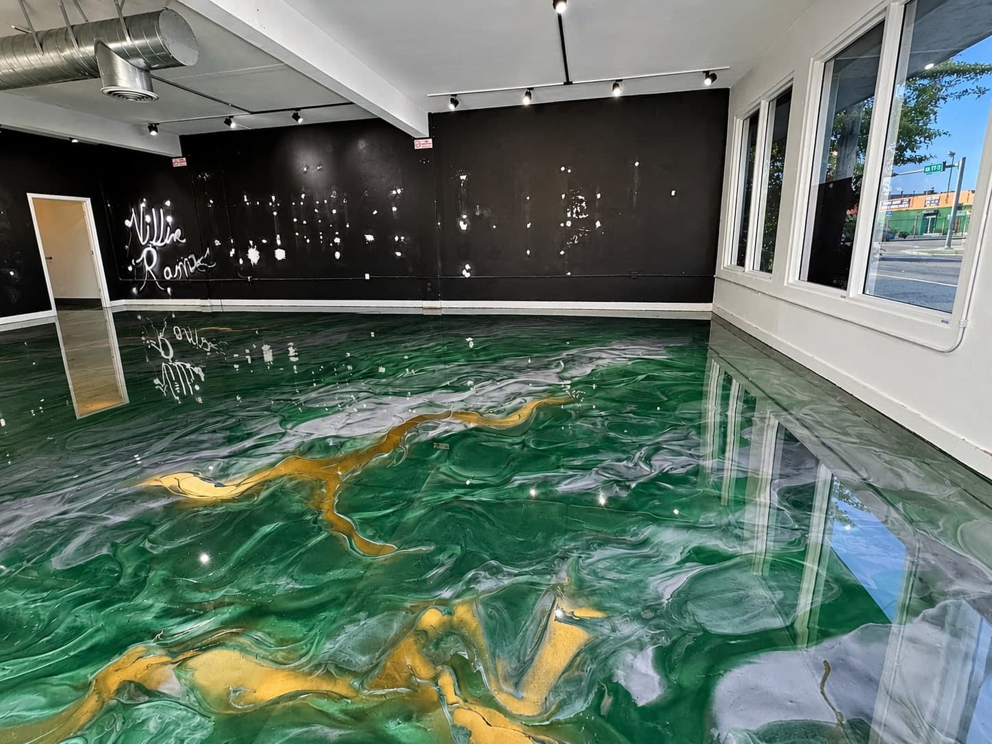 Metallic epoxy floor in deep green with gold veining across a showroom space