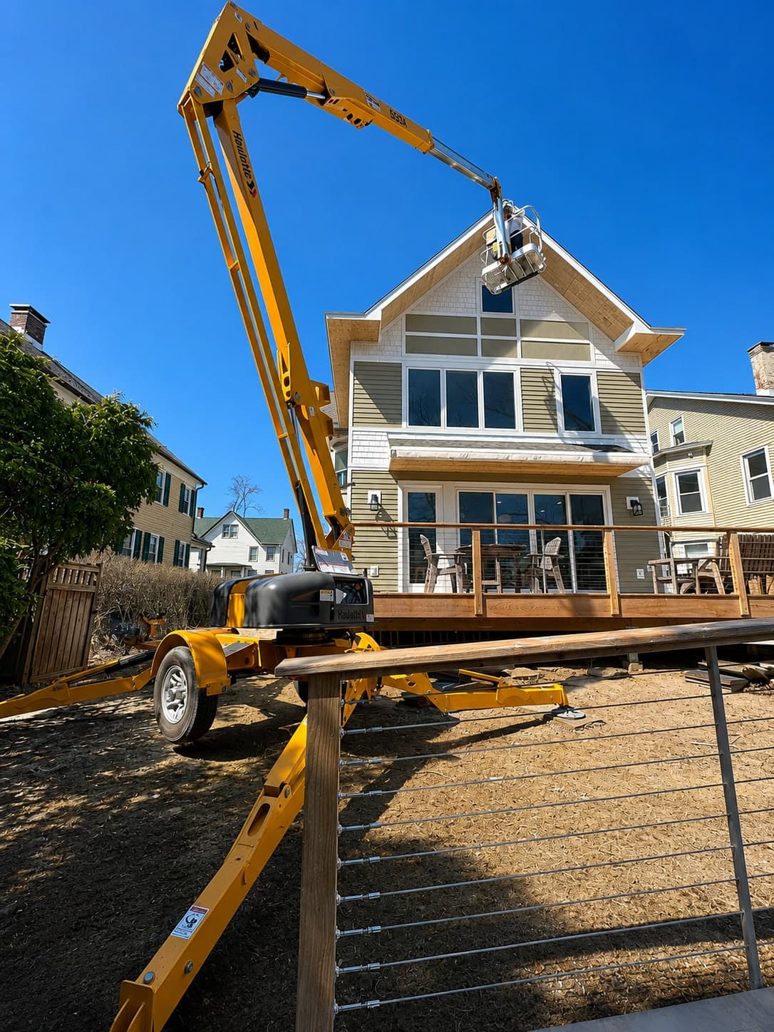 Boom lift set up against a Hudson Valley house to reach the upper elevations for repainting